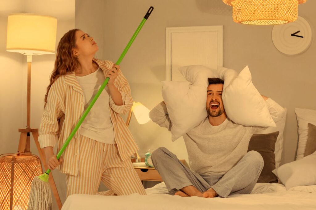 Young,Couple,With,Mop,Suffering,From,Loud,Neighbours,In,Bedroom